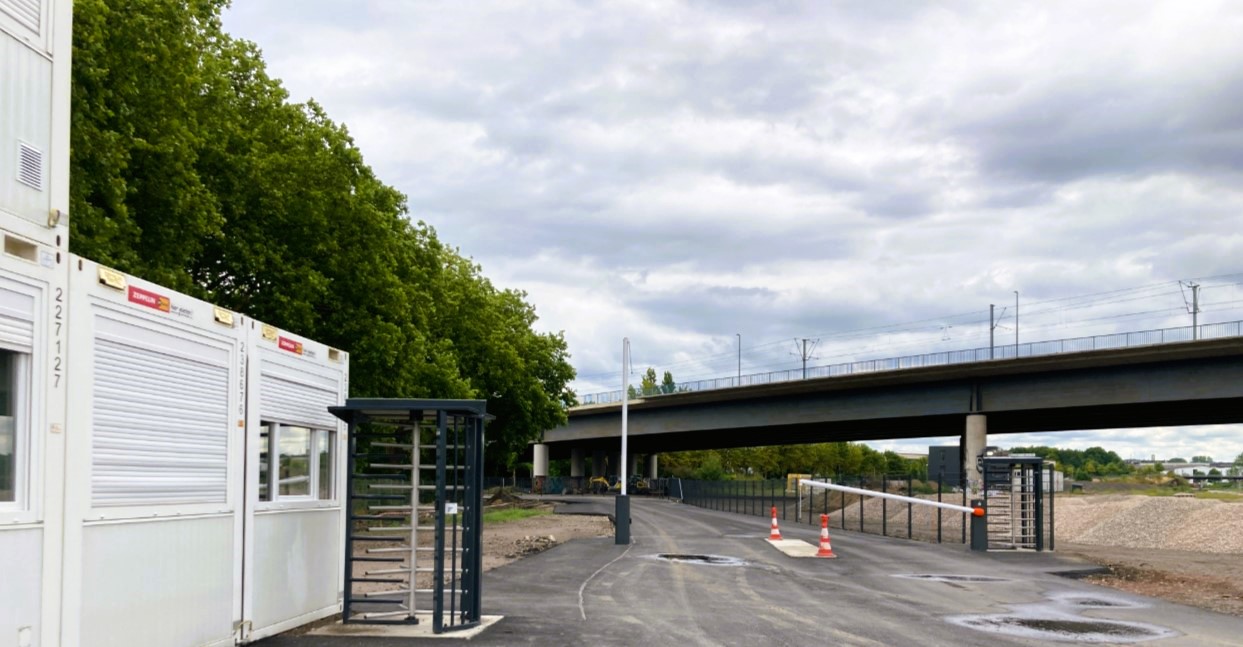 Das Bild zeigt die neue Zufahrt, mit Schrankenanlage und dem Pförtnergebäude