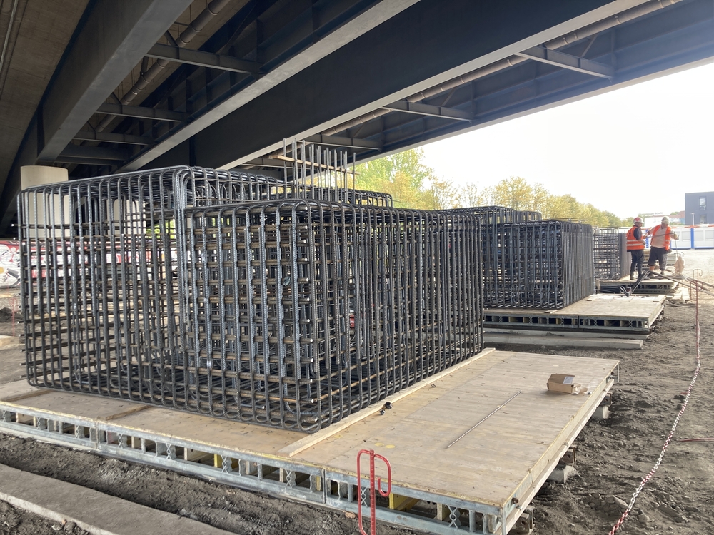 Auf dem Bild sind 2 fertige Bewehrungskörbe zu sehen sowie ein dritter der gerade von Mitarbeitern zusammengebaut wird.